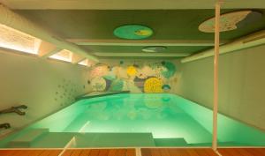 uma piscina num quarto com uma pintura na parede em Kindadom - Maison pour vacances insolites et inoubliables en Belgique em Montzen