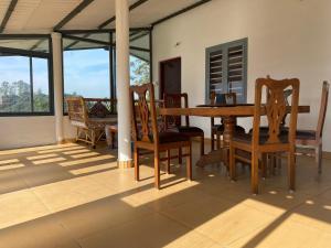a dining room with a table and chairs and windows at Thendral: Delightful homestay on a hill near Ooty in Naduvattam