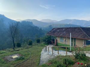 una casa en una colina con montañas en el fondo en Thendral: Delightful homestay on a hill near Ooty, en Naduvattam