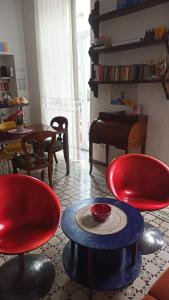 una sala de estar con 2 sillas rojas y una mesa. en Napoli naif, en Nápoles