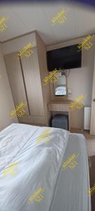 a bedroom with a bed with yellow writing on it at Caravan 521 shuker in Talybont