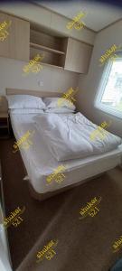 Caravan 521 shuker في Talybont: غرفة نوم مع سرير عليه لافتات صفراء