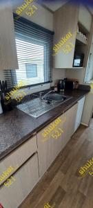 a kitchen with yellow writing on the counters and a sink at Caravan 521 shuker in Talybont