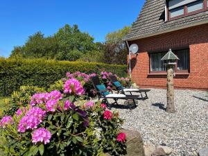 a garden with two chairs and flowers in front of a house at Ferienwohnung im Erdgeschoss mit eingezäunten Garten und Terrasse in Aurich