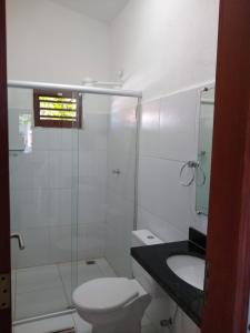 Baño blanco con aseo y lavamanos en Condomínio e Pousada Chalés Sossego do Gostoso, en São José