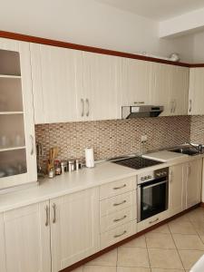 La cuisine est équipée de placards blancs et d'un four avec plaques de cuisson. dans l'établissement Durres Center, à Durrës