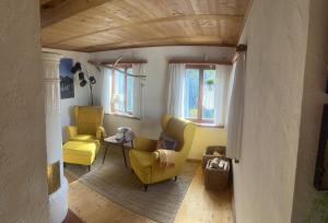Sala de estar con 2 sillas amarillas y mesa en Ferienhaus Kobolzeller Schlößchen a.d.Weinsteige en Rothenburg ob der Tauber