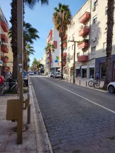 an empty street with palm trees and buildings at Durres Center in Durrës
