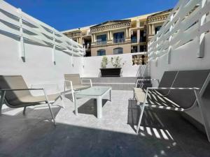 a patio with chairs and a table and a building at Brooklyn Apartments Sliema in Sliema