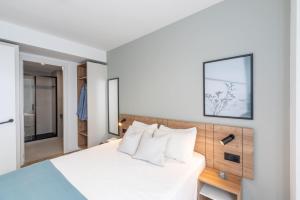 een slaapkamer met een wit bed met witte kussens bij Be Casa - Valdebebas in Madrid