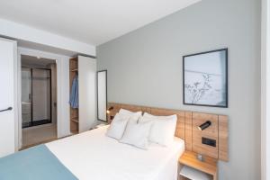 a bedroom with a white bed with white pillows at Be Casa - Valdebebas in Madrid