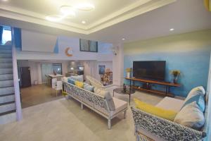 a living room with couches and a flat screen tv at Neverland Hua Hin - Beach Retreat Home in Hua Hin