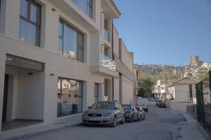 dos autos estacionados en una calle al lado de un edificio en Almazara Suites en Alcalá del Júcar