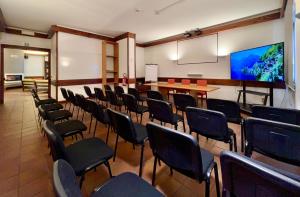 a room with chairs and a table and a flat screen tv at Hotel Bella Venezia in Latisana