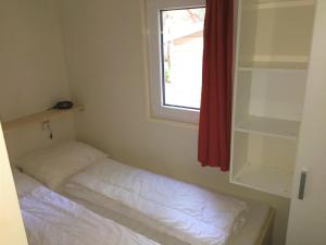 um pequeno quarto com uma cama e uma janela em Greenchalets Costa Brava Palamos em Palamós