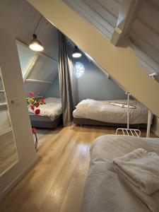 a attic room with two beds and a staircase at Vakantiehuis BijSaar in Noordwijk