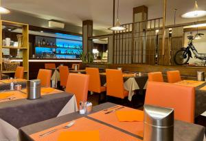 a restaurant with tables and orange chairs and a bar at Hotel Bella Venezia in Latisana +21 photos