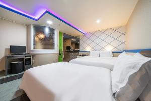 MU HOTEL في بوسان: غرفة فندقية بسريرين وتلفزيون