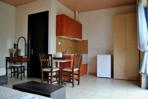 eine Küche mit einem Tisch und Stühlen sowie einem Kühlschrank in der Unterkunft Iliovasilema Hotel in Mitikas