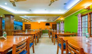 蒙納的住宿－Itsy By Treebo -Classiyo Munnar Crown Resorts，餐厅设有木桌和椅子,拥有绿色的墙壁