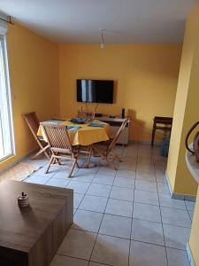 a living room with a table and chairs and a tv at Appartement F2 centre-ville Saint-André in Saint-André