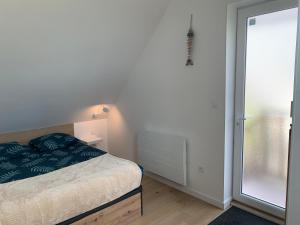 a bedroom with a bed and a sliding glass door at La Pose Normande in La Cerlangue