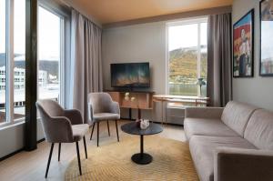 uma sala de estar com um sofá, cadeiras e janelas em Skaret by Vander em Tromsø