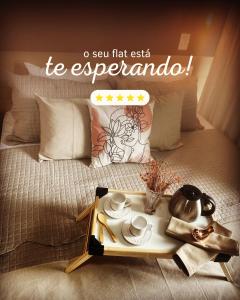Una cama con una bandeja con un set de té. en Flat B306 Village Aldeia das Águas, en Barra do Piraí