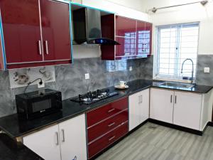 a kitchen with red cabinets and a microwave at Edge of Islamabad Entrance in Islamabad