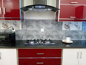 a kitchen with red cabinets and a stove top oven at Edge of Islamabad Entrance in Islamabad