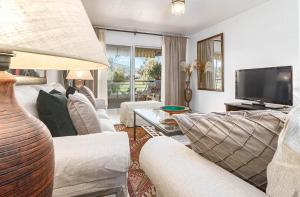 sala de estar con muebles blancos y TV de pantalla plana en Guadavillas 320, en Marbella