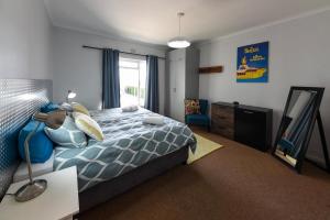 a bedroom with a bed and a desk and a mirror at Die Brandhuis Sleeps 4, One minute walk to the Beach! in Gordonʼs Bay