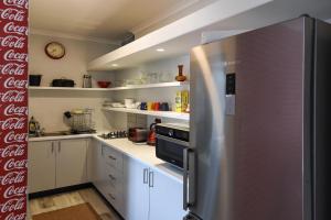 a kitchen with a stainless steel refrigerator and white cabinets at Die Brandhuis Sleeps 4, One minute walk to the Beach! in Gordonʼs Bay