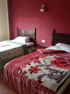 a bedroom with two beds and a red wall at Hotel Holidays Inn - A Family Running Guest House in Meghauli