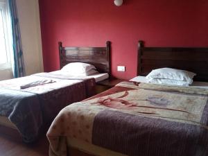 two beds in a room with a red wall at Hotel Holidays Inn - A Family Running Guest House in Meghauli