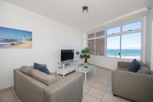 a living room with two couches and a flat screen tv at 72 Sea Lodge Umhlanga Rocks in Durban