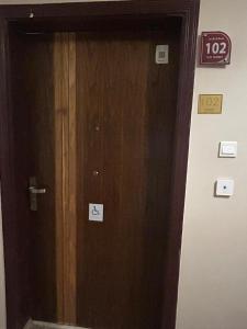 Una puerta de madera en una habitación con un cartel. en Layali Alandlous Furnished Units en Al Qunfudhah