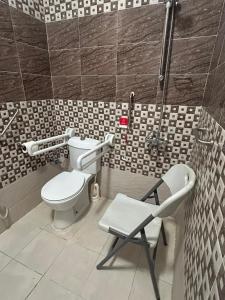 a bathroom with a toilet and a chair in it at Layali Alandlous Furnished Units in Al Qunfudhah