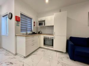 a kitchen with white cabinets and a blue couch at Brooklyn Apartments Sliema in Sliema