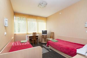 a room with two beds and a desk and a television at Balvi Hotel in Balvi