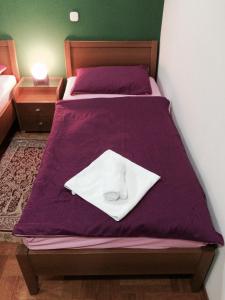 a bed with a purple comforter with a white shirt on it at Guest House Šeperić in Jastrebarsko