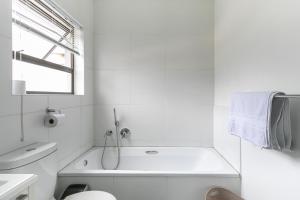 a white bathroom with a tub and a sink at K Luxe Apartment in Sandton