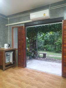 an open sliding glass door with a view of a garden at Mind's Homestay มายด์โฮมสเตย์ in Kampong Huaibū