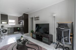 a living room with a television and a living room with a table at K Luxe Apartment in Sandton