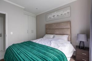 a bedroom with a large bed with a green blanket at K Luxe Apartment in Sandton