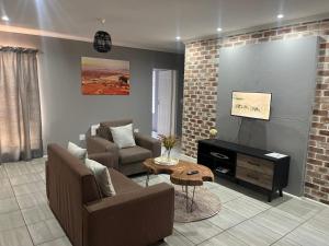a living room with a couch and chairs and a table at Otis Self Catering in Walvis Bay +17 photos