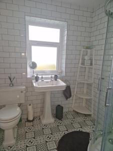 uma casa de banho com um lavatório, um WC e uma janela. em The Haven em Beadnell