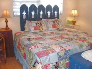 een slaapkamer met een bed met een quilt bij Palm Cottage #54605 in Holmes Beach