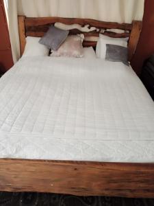 una cama de madera con sábanas blancas y almohadas. en Black gate en Nanyuki