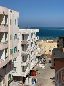 a tall white building with the ocean in the background at Rent a Home Hurghada in Hurghada